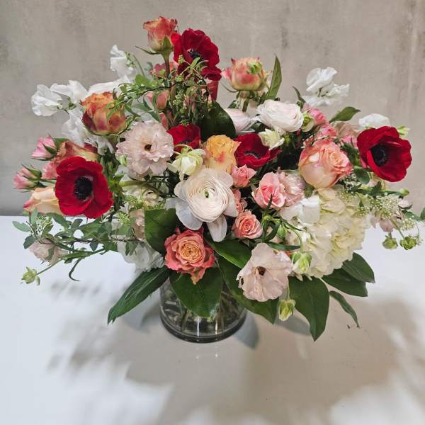 Mixed bouquet of red, pink, and white flowers in a glass vase