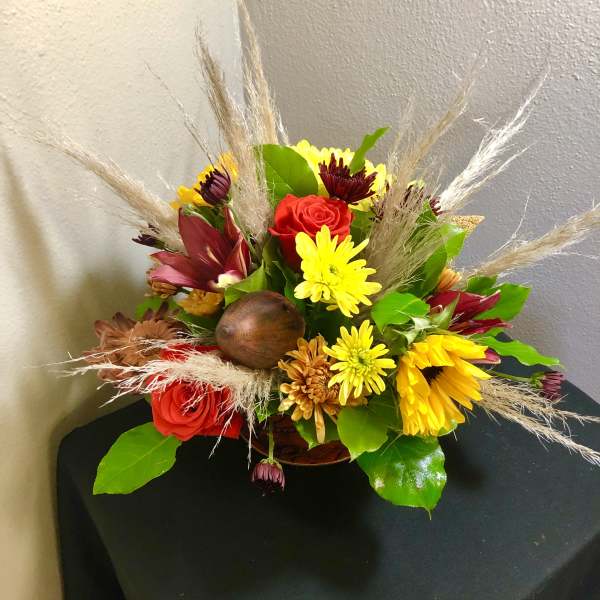 Mixed bouquet with red roses and yellow daisies in a low container