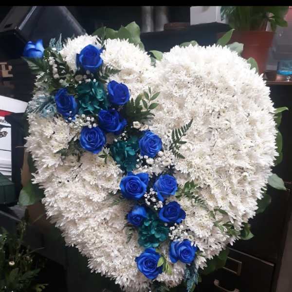 Heart-shaped white floral arrangement with blue roses