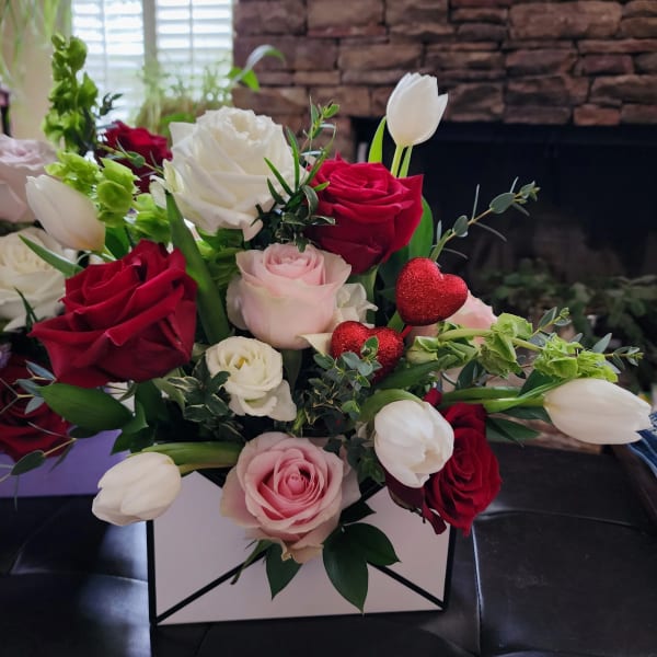 Bouquet of red, pink, and white roses with white tulips in a box