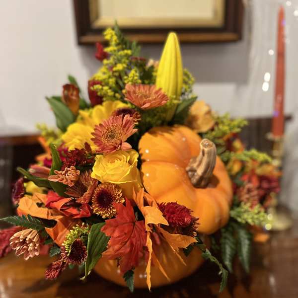 Autumn floral arrangement in a pumpkin with yellow, orange, and red blooms