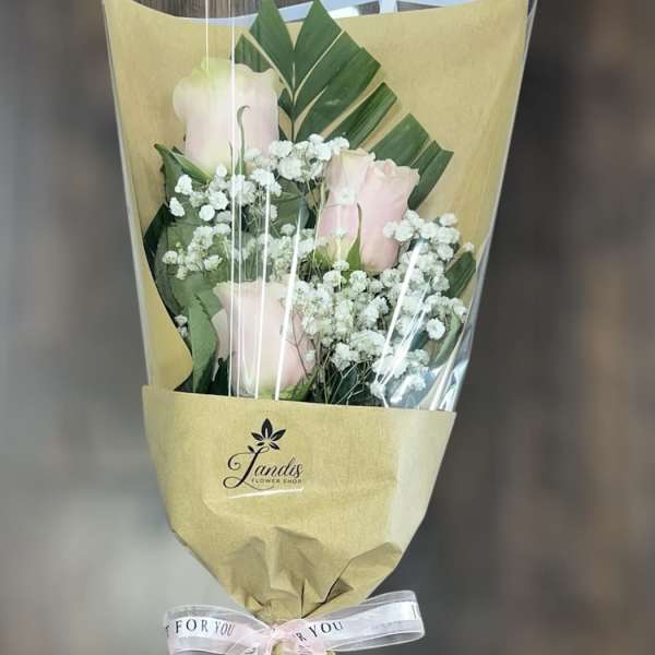 Bouquet of pale pink roses with white baby's breath in tan wrapping