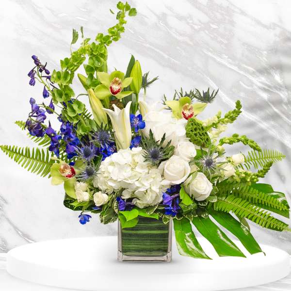 Mixed bouquet in a square glass vase with white, green, and blue flowers