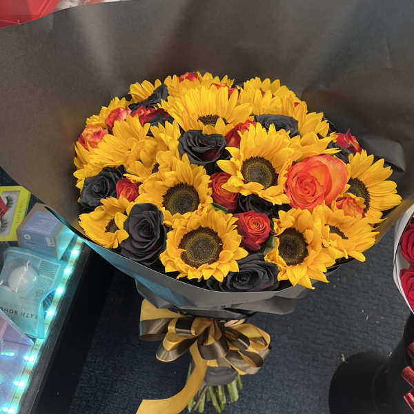 Bouquet of yellow sunflowers and dark roses wrapped in black paper