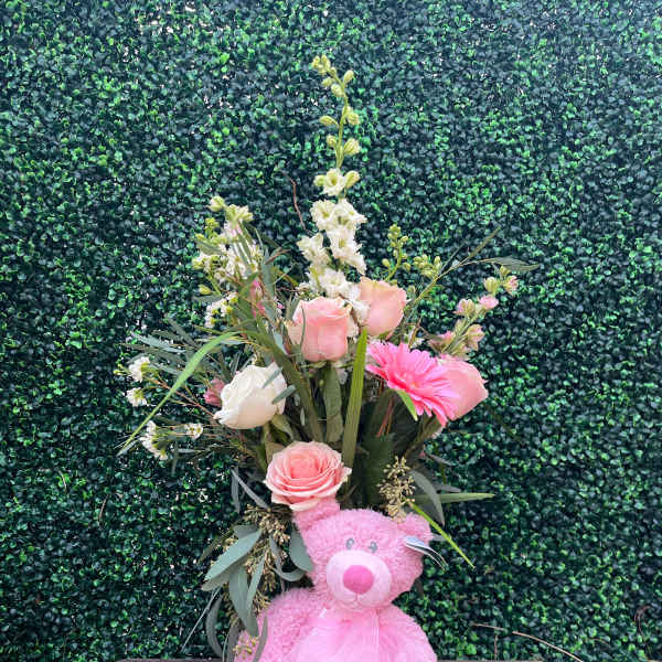 Pink teddy bear with a floral bouquet and sheer ribbon