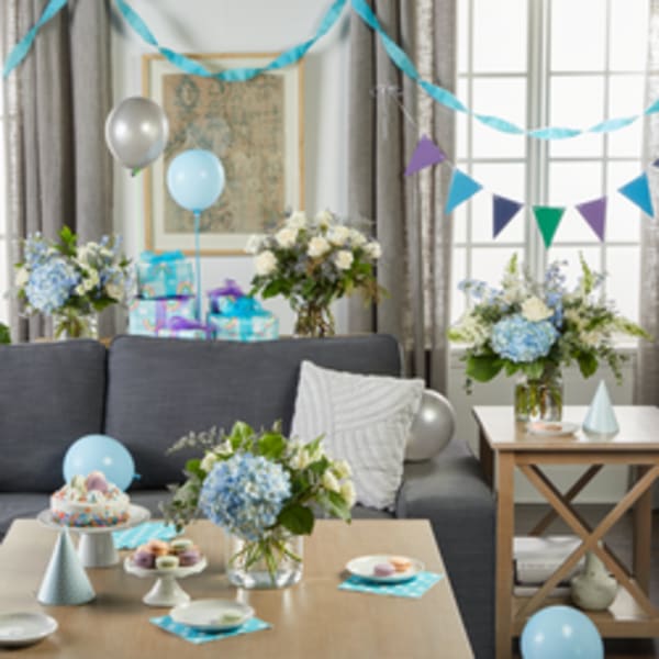 Blue and white floral arrangements on tables in a decorated party room
