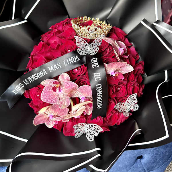 Round bouquet of red roses with pink orchids and decorative ribbons