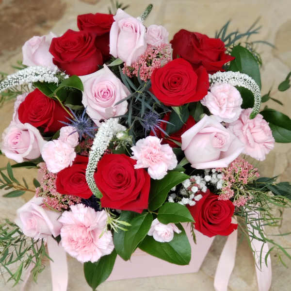 Bouquet of red and pale pink roses with pink carnations in a pink box