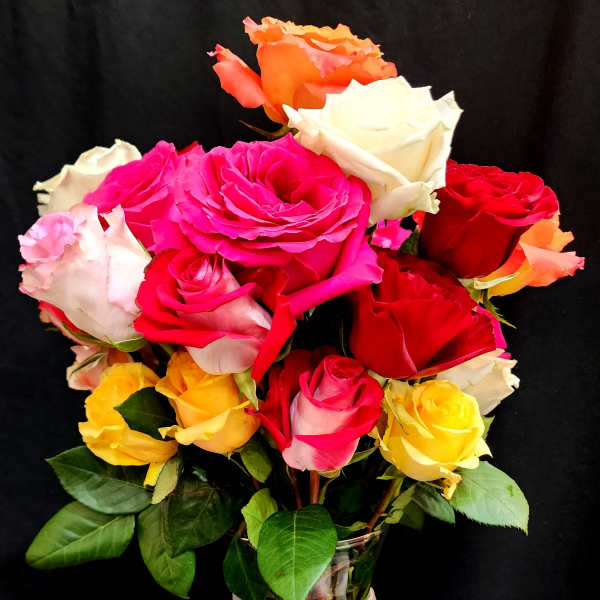 Bouquet of multicolored roses in a glass vase with a white ribbon