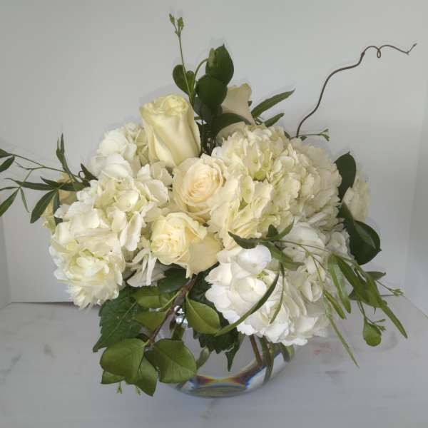 White roses and hydrangeas in a clear glass vase