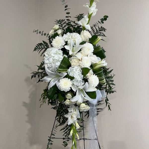 Tall white floral standing spray with lilies and mums on an easel