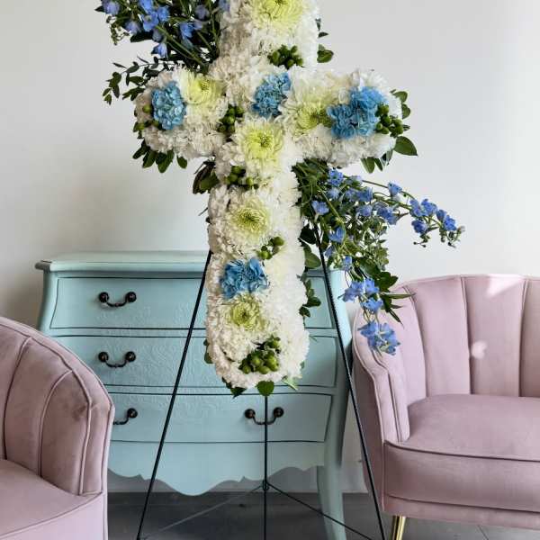 Large floral cross on a stand with white, blue, and green flowers