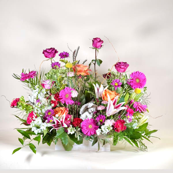 Mixed pink and orange floral arrangement in a white container