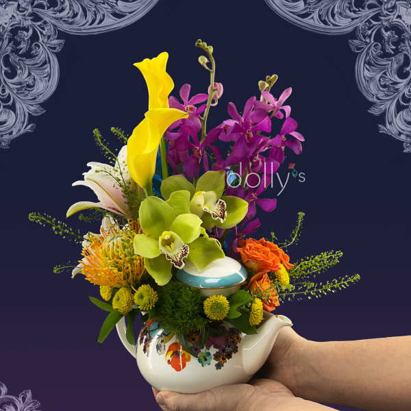 Colorful bouquet in a floral teapot with orchids, calla lilies, and roses