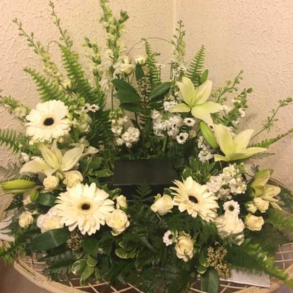 White floral sympathy arrangement with lilies and gerbera daisies