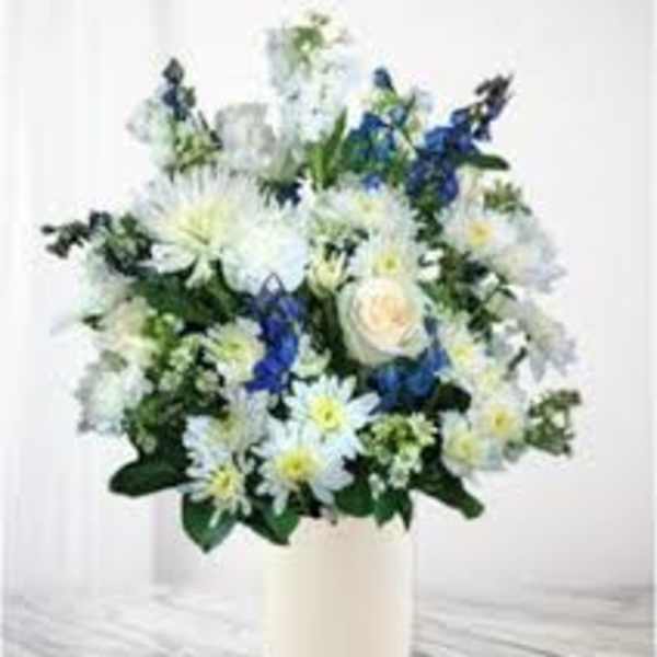 White and blue flowers arranged in a tall white vase
