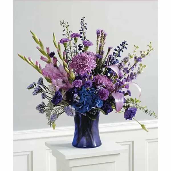 Purple and blue mixed flower arrangement in a dark blue vase