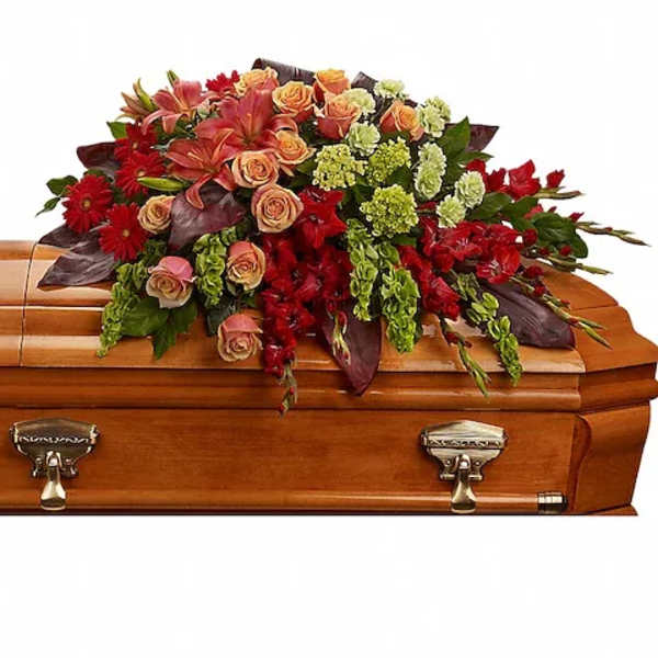 Floral casket spray with red and peach flowers on a wooden casket