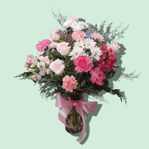 Pink and white mixed bouquet in a glass vase with a pink ribbon