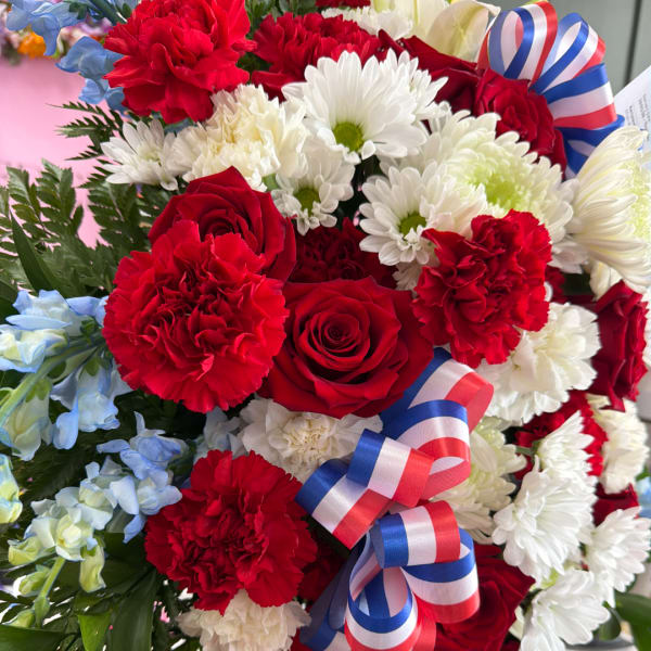 Bouquet of red roses, white daisies, and red carnations with ribbon bows