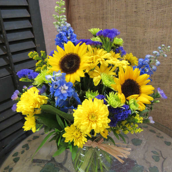 Yellow sunflowers and blue flowers in a glass vase