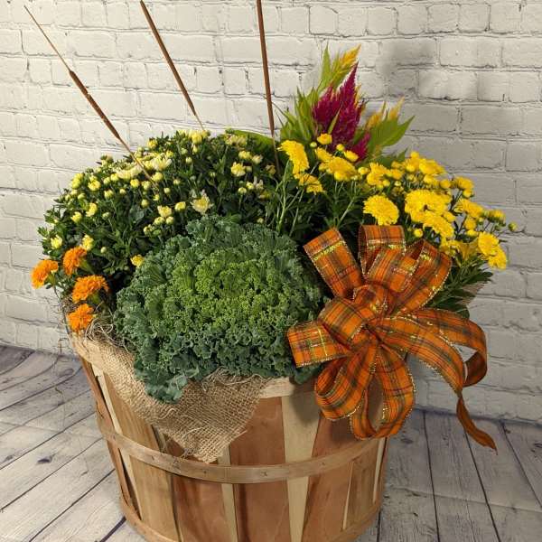 Fall flower arrangement in a wooden basket with yellow and orange blooms