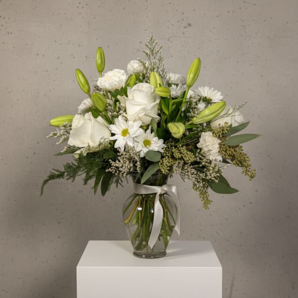 White roses and daisies in a glass vase with a satin ribbon