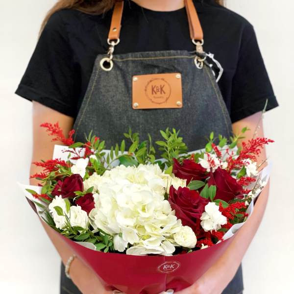 Bouquet of red roses and white hydrangeas wrapped in red paper