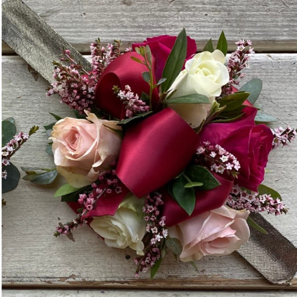 Hand-tied bouquet of pink, white, and red roses with ribbon wrap