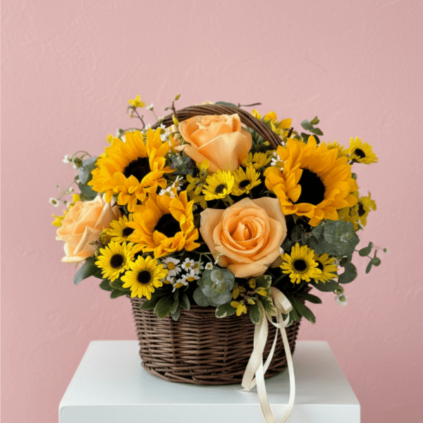 Basket arrangement of yellow sunflowers, peach roses, and small yellow daisies with a ribbon bow.