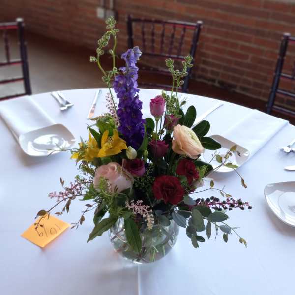 Mixed floral centerpiece in a clear glass bowl on a white tablecloth