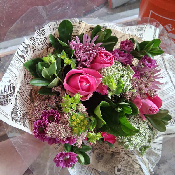 Bouquet of pink roses and purple flowers wrapped in printed paper