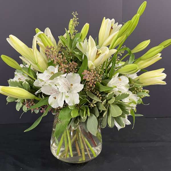 White lilies and alstroemeria in a clear glass vase