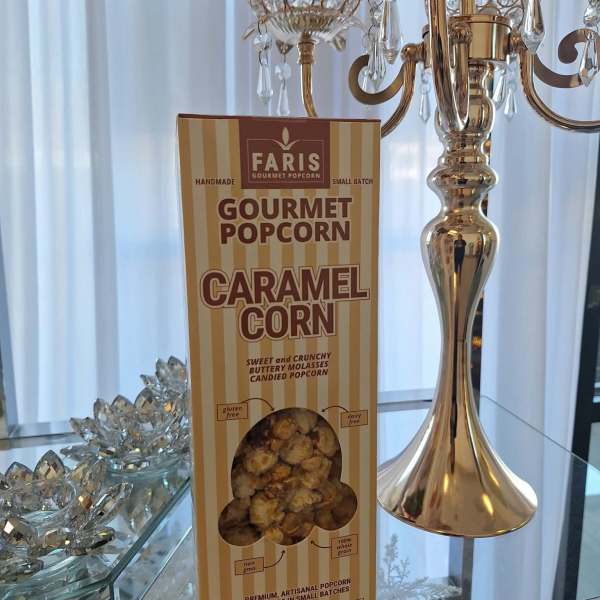 Box of caramel gourmet popcorn on a mirrored table beside a gold candelabra