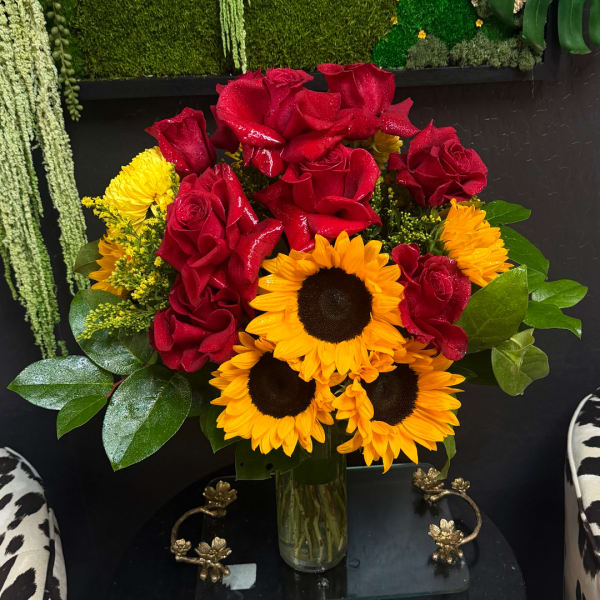 Bouquet of red roses and yellow sunflowers in a glass vase