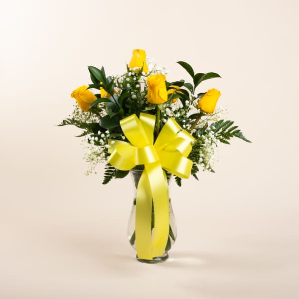 Yellow roses in a glass vase with a large yellow ribbon