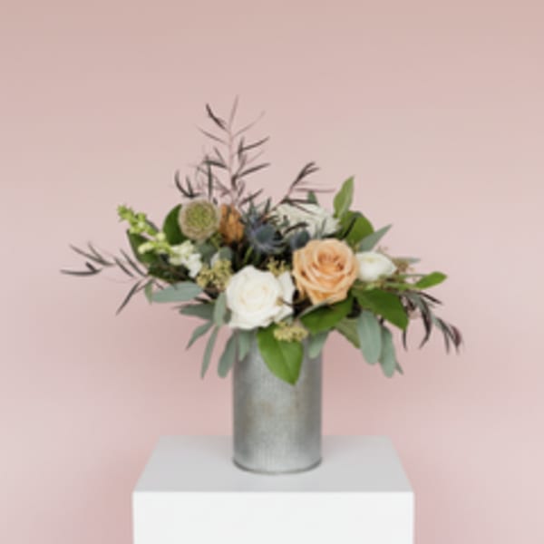 Mixed bouquet of roses and greenery in a silver vase