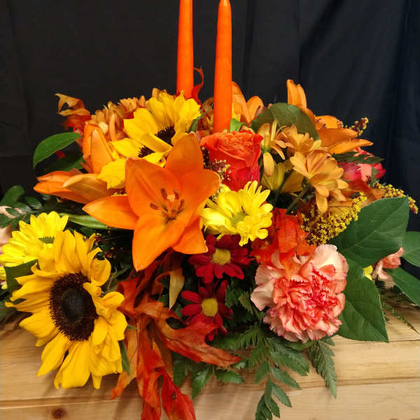Autumn bouquet with sunflowers, lilies, carnations, and two orange candles