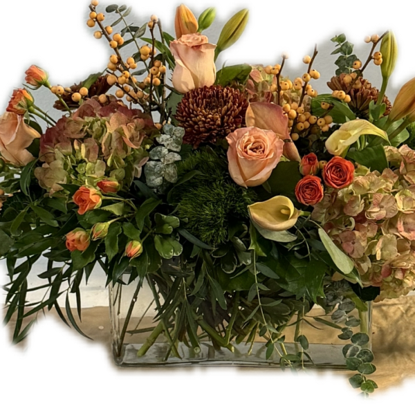 Mixed floral arrangement in a clear rectangular vase with roses and lilies