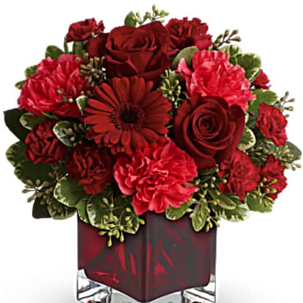 Red roses and carnations in a square glass vase