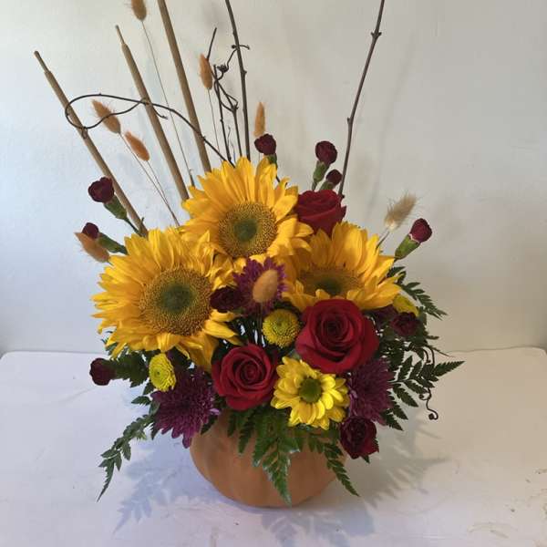 Sunflower and red rose arrangement in a round vase with tall branches
