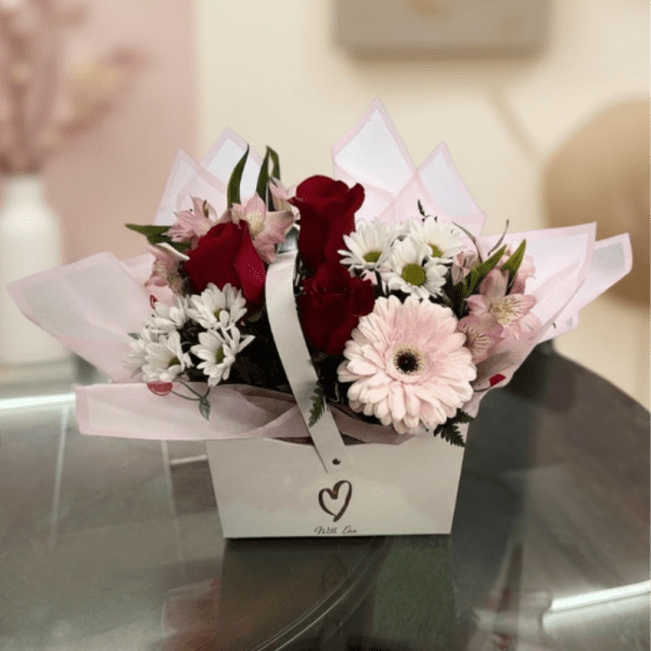 Bouquet of red roses, pink gerbera daisies, and white daisies in a gift box