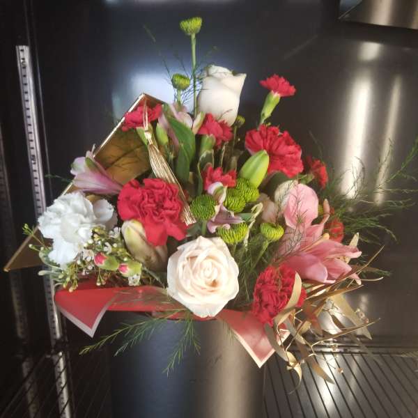Mixed bouquet of red, white, and pink flowers in a black hatbox