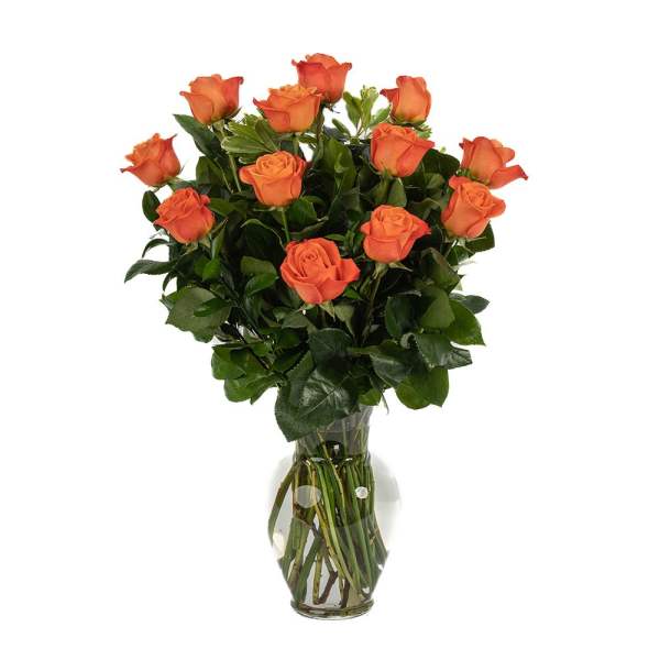 Dozen orange roses arranged in a clear glass vase with water