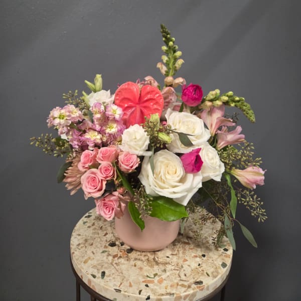Pink and white rose arrangement in a blush vase with mixed blooms
