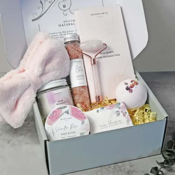 Spa gift box with pink headband, rose quartz roller, bath salts, candle, bath bomb, and body products