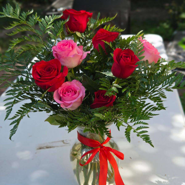Bouquet of red and pink roses in a glass vase with a red ribbon