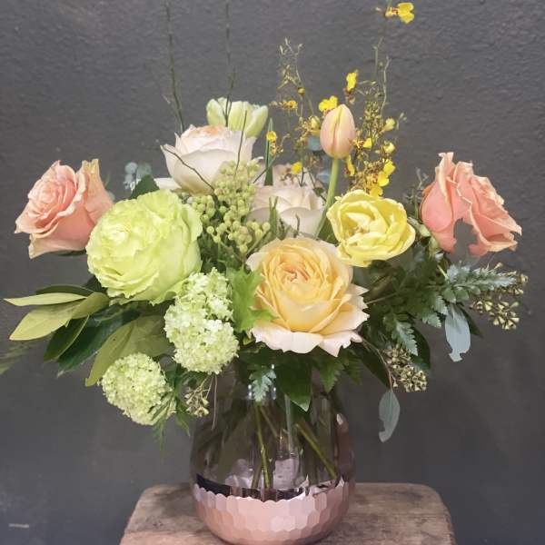 Mixed pastel roses and blooms arranged in a glass vase