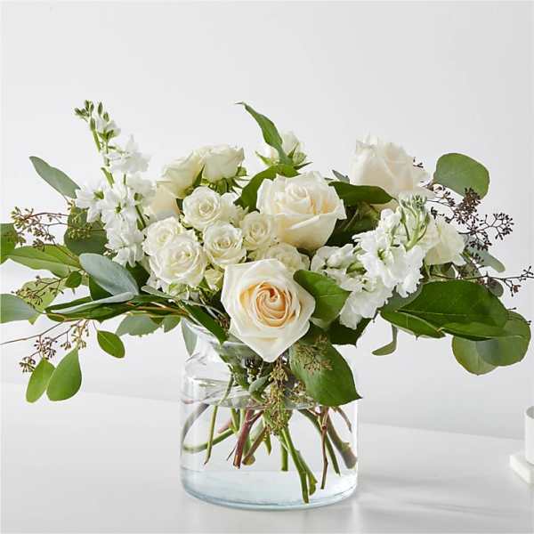 White roses and small white blooms in a clear glass vase