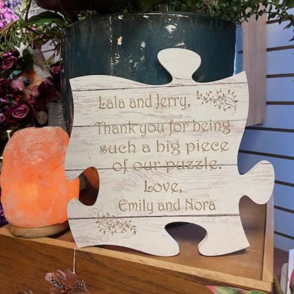 Puzzle-shaped thank-you sign beside flowers and a salt lamp